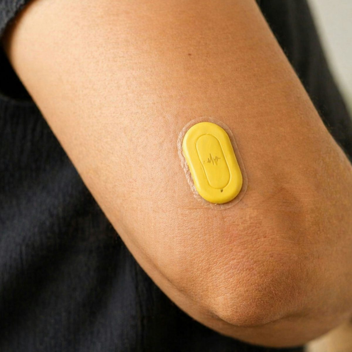 A small adhesive monitoring device worn on a person's upper arm